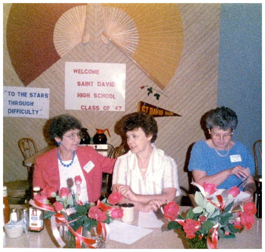 St. David 1987 reunion, some class members at dining table in front of school motto